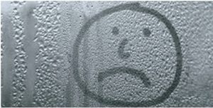 sad face drawn on window with bad condensation