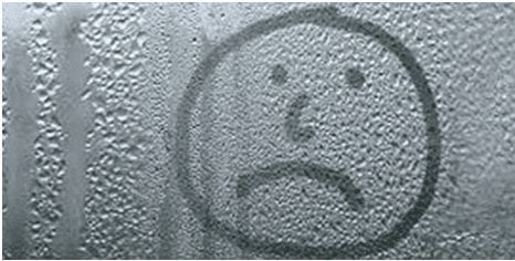Unhappy face drawn on a window with bad condensation