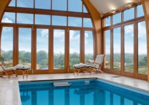 gallery pool with massive arched wooden windows and lift and slide patio doors