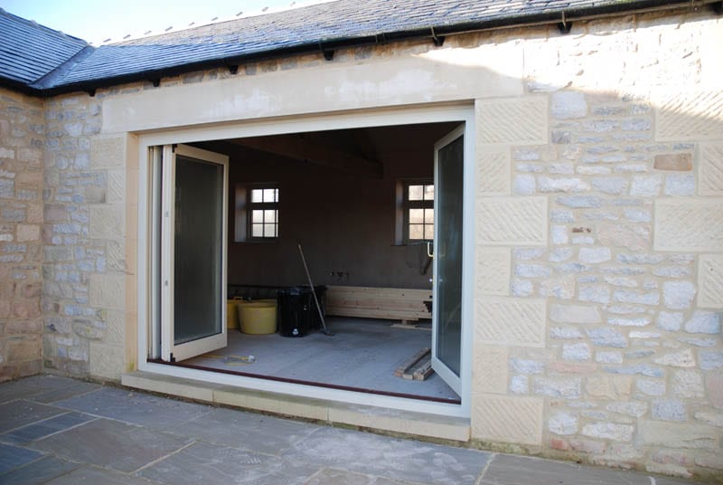Main image of Halifax heritage bifold doors open in a barn conversion by gowercroft joinery