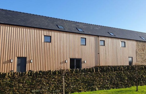 Rear view of Dunston Barn showing timber cladding and typical barn conversion square windows and roof lights