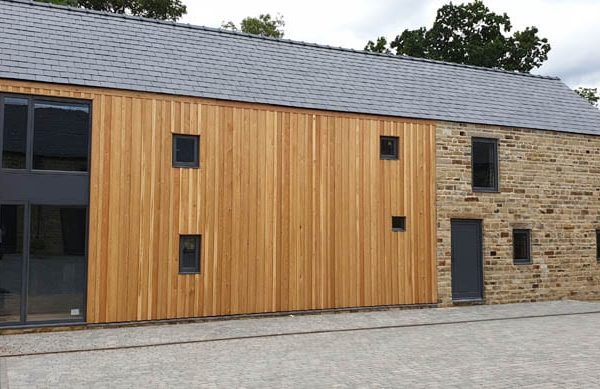 Low angle photo of the cladding to the rear of dunston barn with doors and timber windows for barn conversions