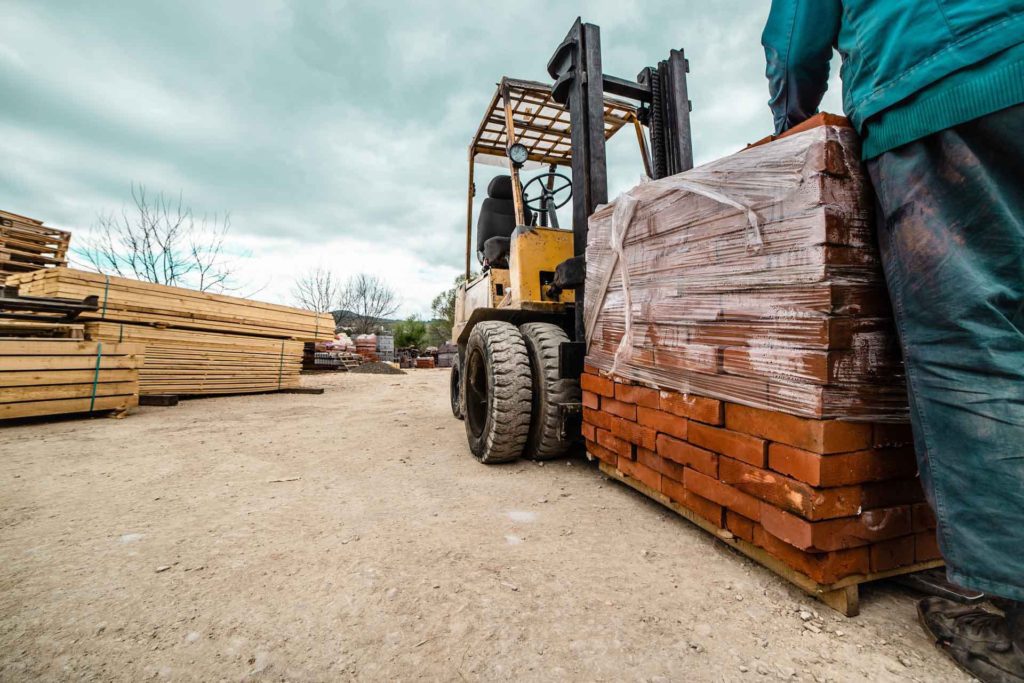 Who Sells Timber Windows? A fork truck delivering a pallet of bricks to a builders merchant where you can buy timber windows from