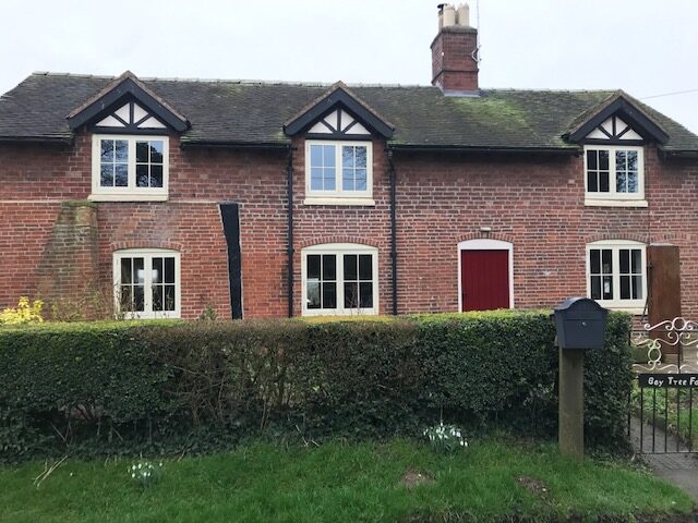 A charming brick cottage featuring off-white timber flush casement windows, highlighting the Richmond Flush Casement range by Gowercroft Joinery. The windows blend seamlessly with the traditional aesthetics of the property while providing modern performance standards.