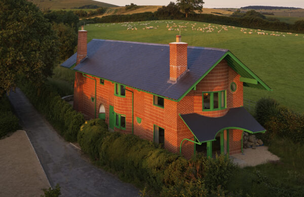 Red House External Elevation with Hardwick Casements and Melbourne Doors: An exterior shot of The Red House, showcasing the building's bold design. The handmade red brickwork contrasts with bright green Hardwick casement windows and Melbourne timber doors, which punctuate the façade. The house, sitting on a hillside amidst rolling fields, features exaggerated overhanging green eaves and a steep-pitched slate roof. The vibrant green timber windows and doors add a playful touch to the traditional brick structure, with the countryside extending into the distance, reinforcing the house's connection with its natural surroundings.