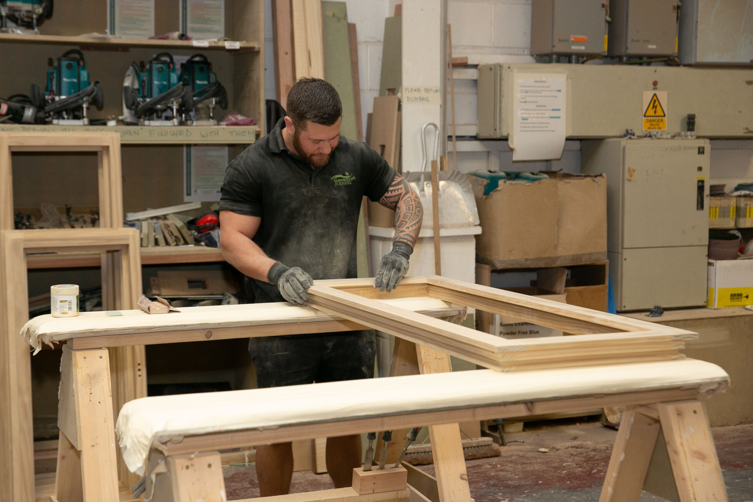 Joiner sands window frame in factory setting.