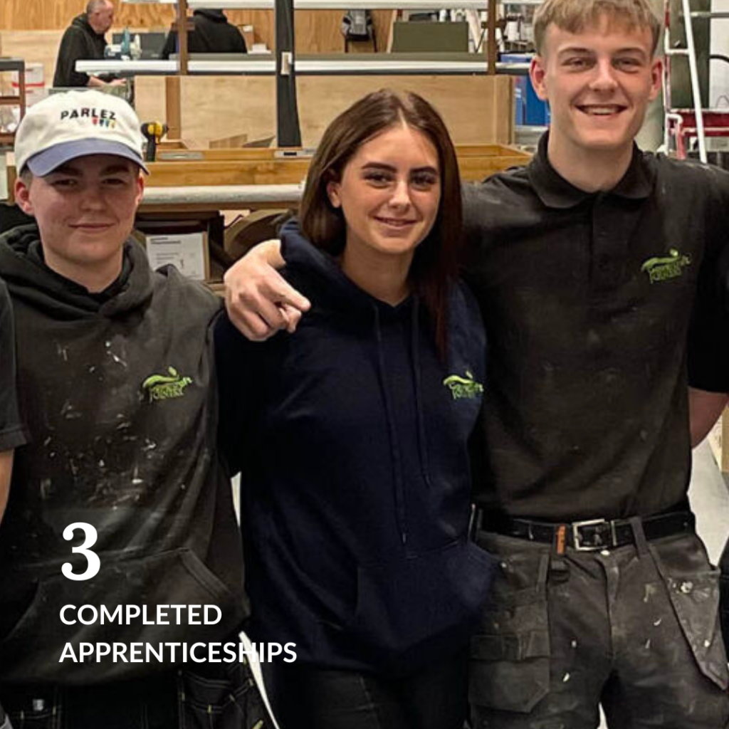 Three smiling Gowercroft apprentices celebrating the completion of their joinery apprenticeships in 2024.